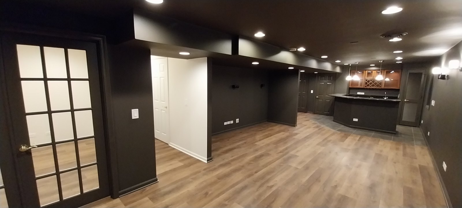 Finished basement with dark walls and wood-look flooring