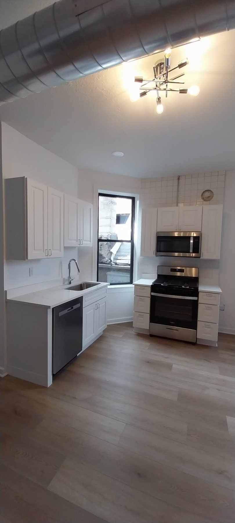 Completed kitchen with white cabinets and wood-look flooring